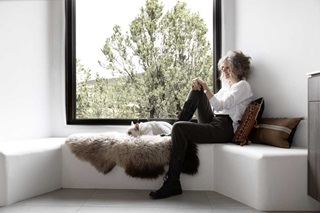 A woman and a French bulldog sitting on a white bench next to a Marvin Ultimate window with black frame.