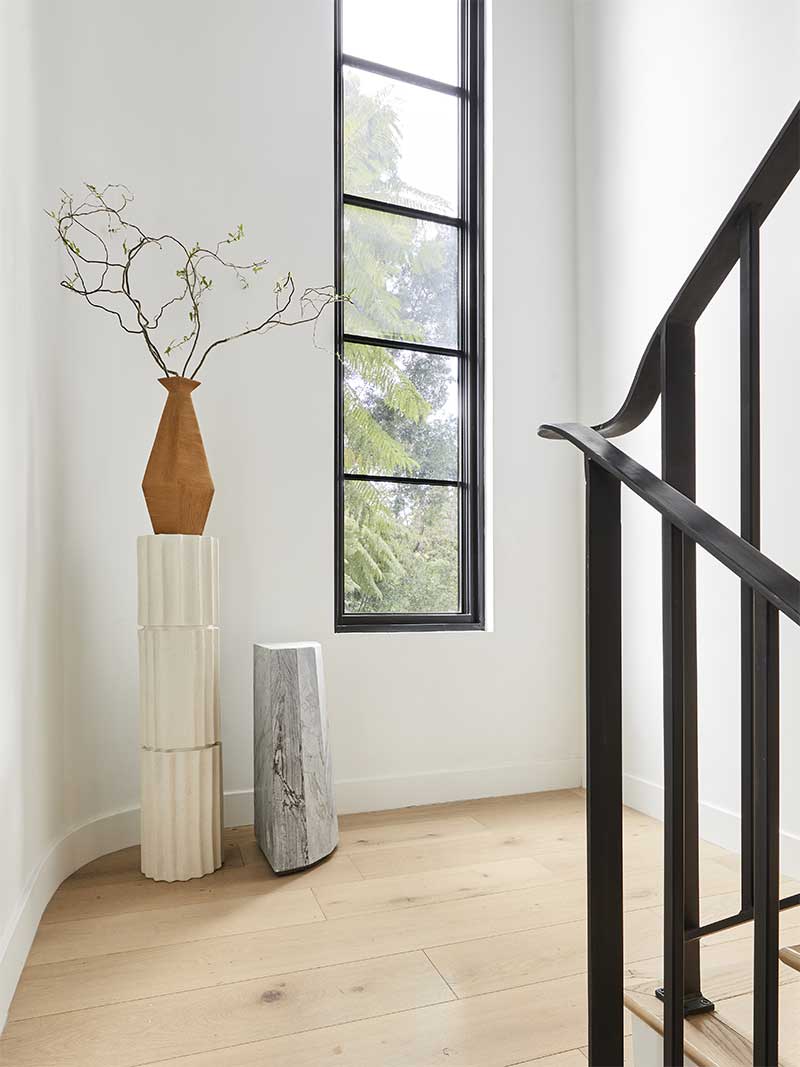 The staircase in the Bobby Berk Firm’s office, featuring a tall retangular Marvin Ultimate window to bring in lots of light to the space.