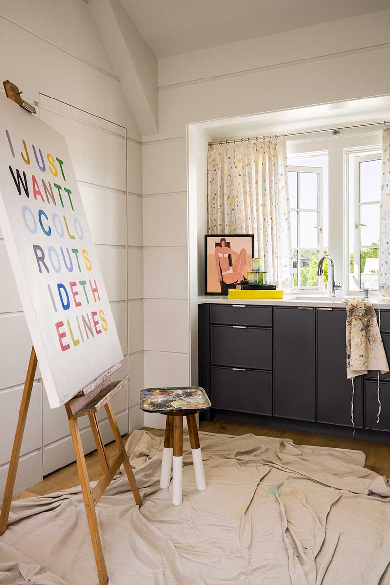 An artist's workspace with an easel, drop cloth, and apron, near a Marvin Ultimate Casement Push-Out window.