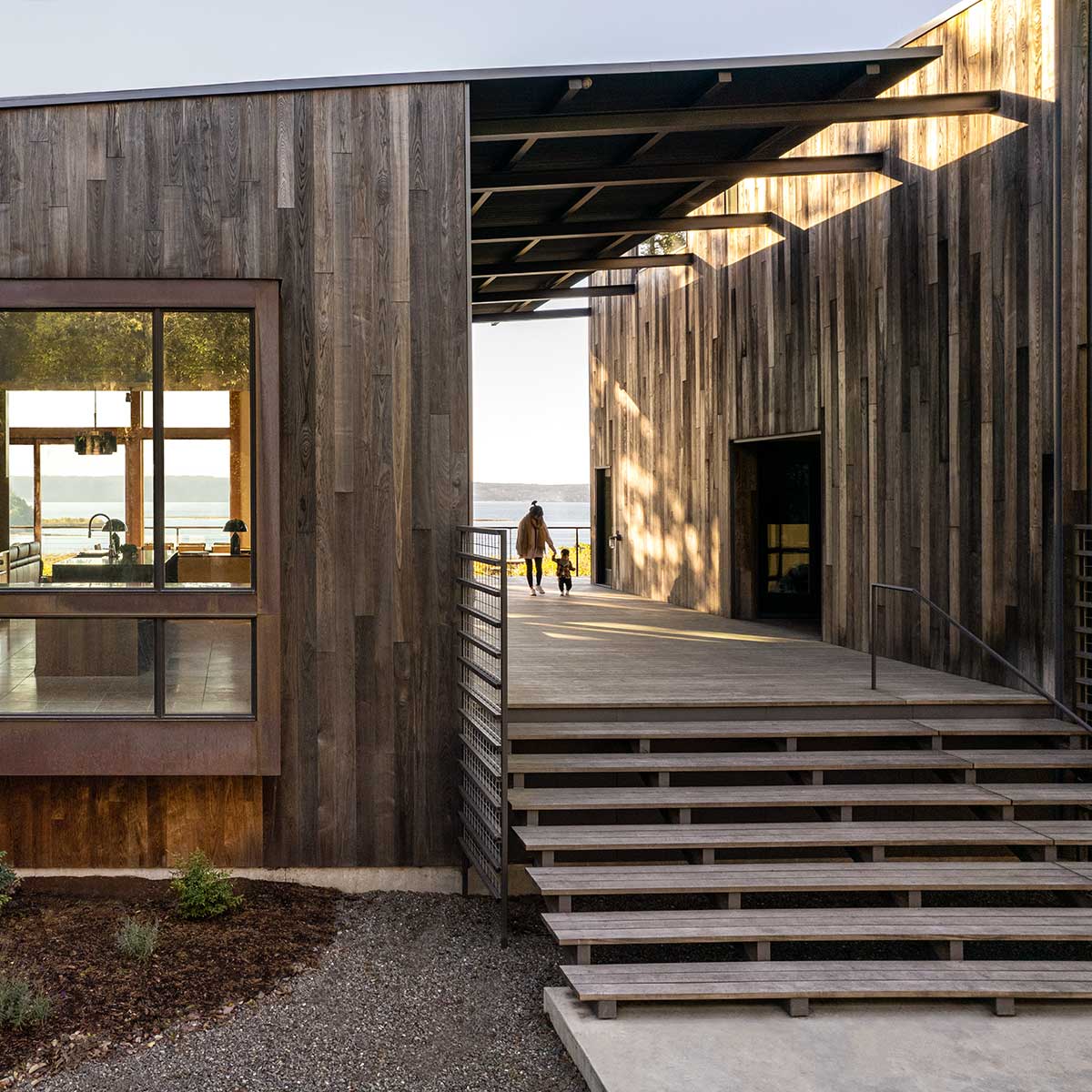 A mother and child walking along the dogtrot of a modern home on Puget Sound.