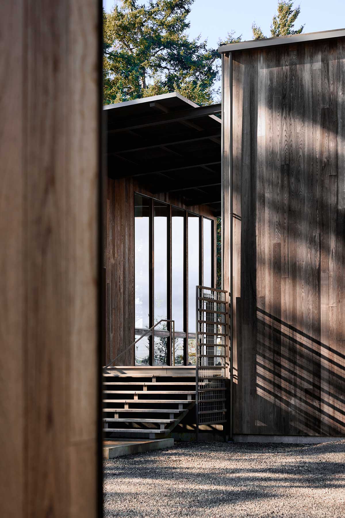 An exterior photo of a modern home on Marrowstone Island showing the stairs up to the dog trot and Marvin Ultimate Direct Glaze windows.