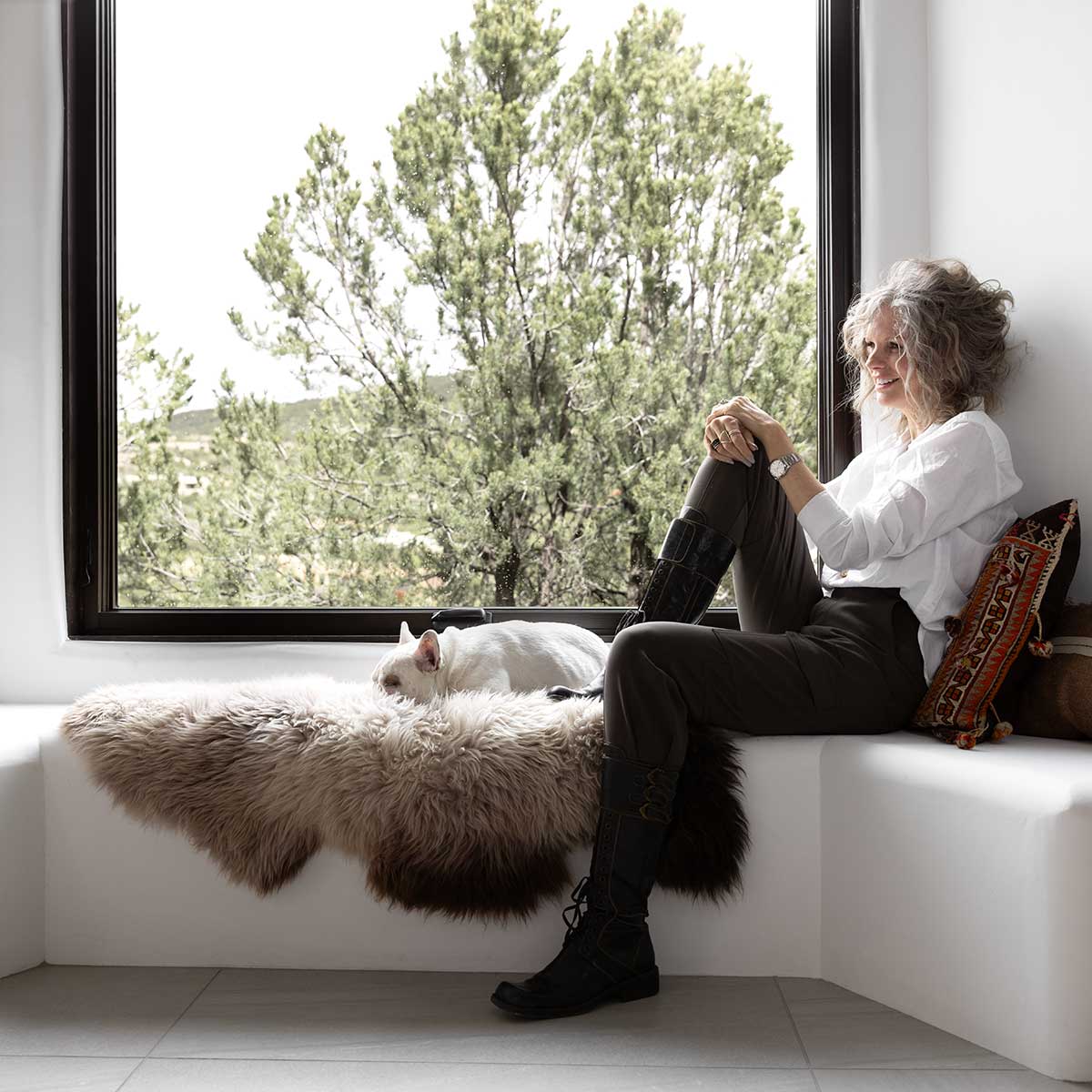 A woman and a French bulldog sitting on a bench beneath a Marvin Ultimate Awning Narrow Frame window.