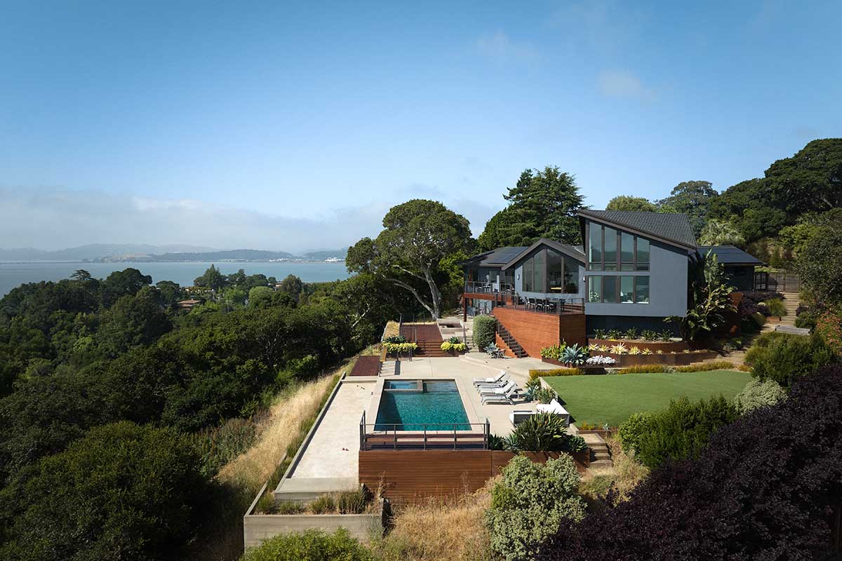 A drone photo of the exterior of a home overlooking a bay in San Rafael, California, featuring a pool and Marvin Ultimate Casement and Ultimate Polygon windows.