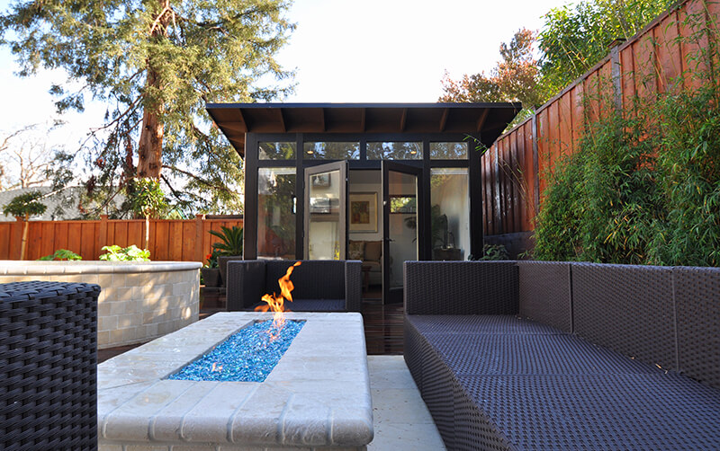 A backyard Studio Shed next to a patio fire pit.