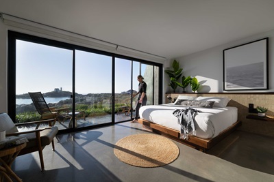 A view of the Nubble Lighthouse from inside a Viewpoint Hotel private guest suite with person exiting the room through a Marvin Elevate Sliding door.