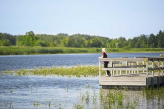 A person standing on a pier overlooking a lake