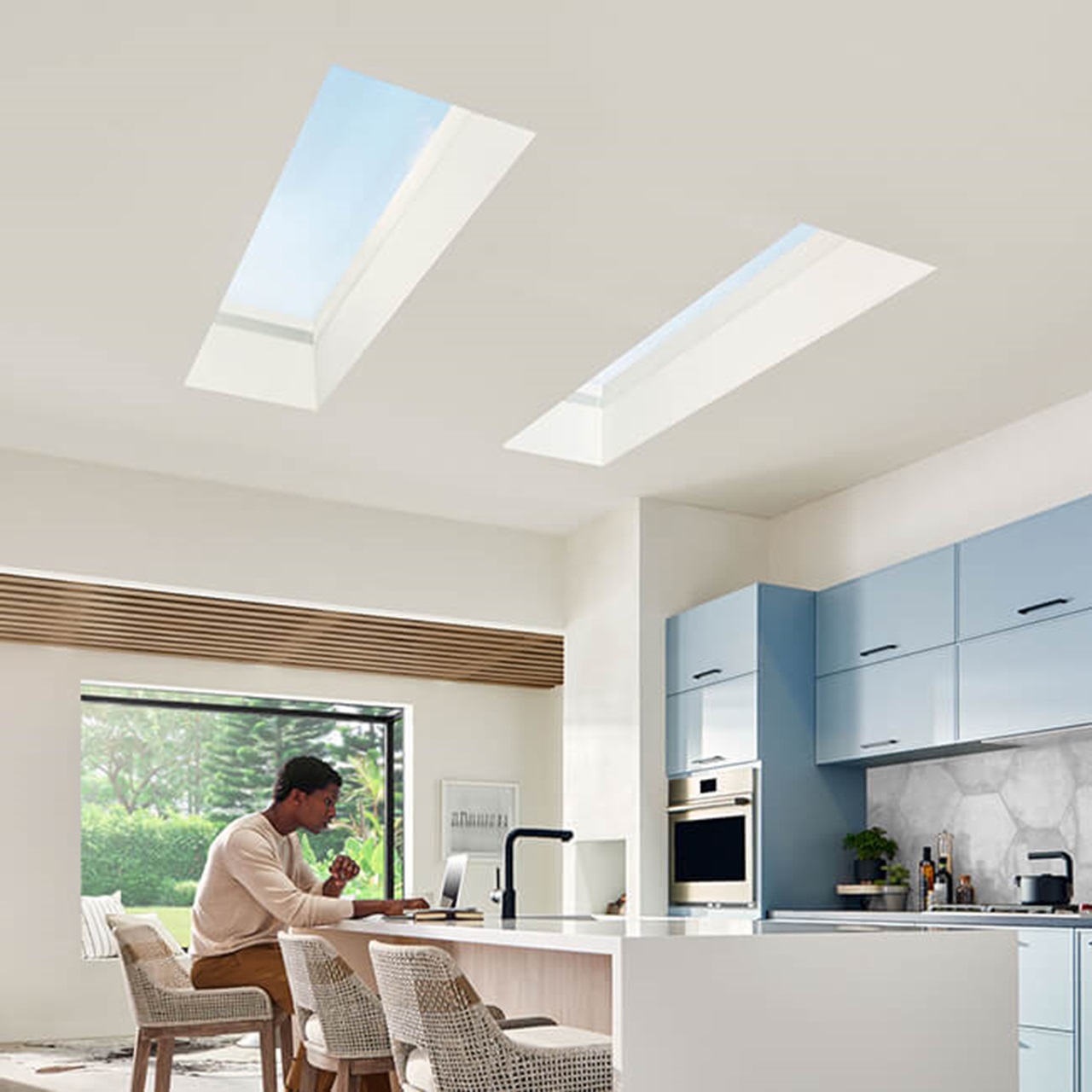 Interior of home with young man sitting in Kitchen with Marvin Skycove window box and Marvin Awaken Skylights