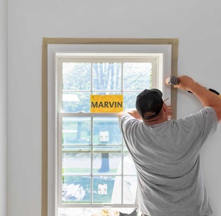 A man replacing a window in a house.